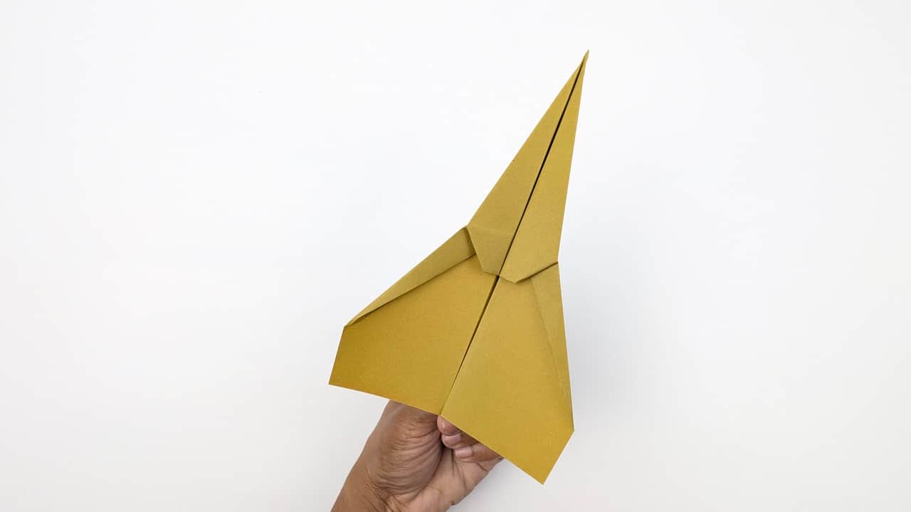 Hold the airplane from below the spine, with your thumb and fingers on either side of the body near the center of gravity.