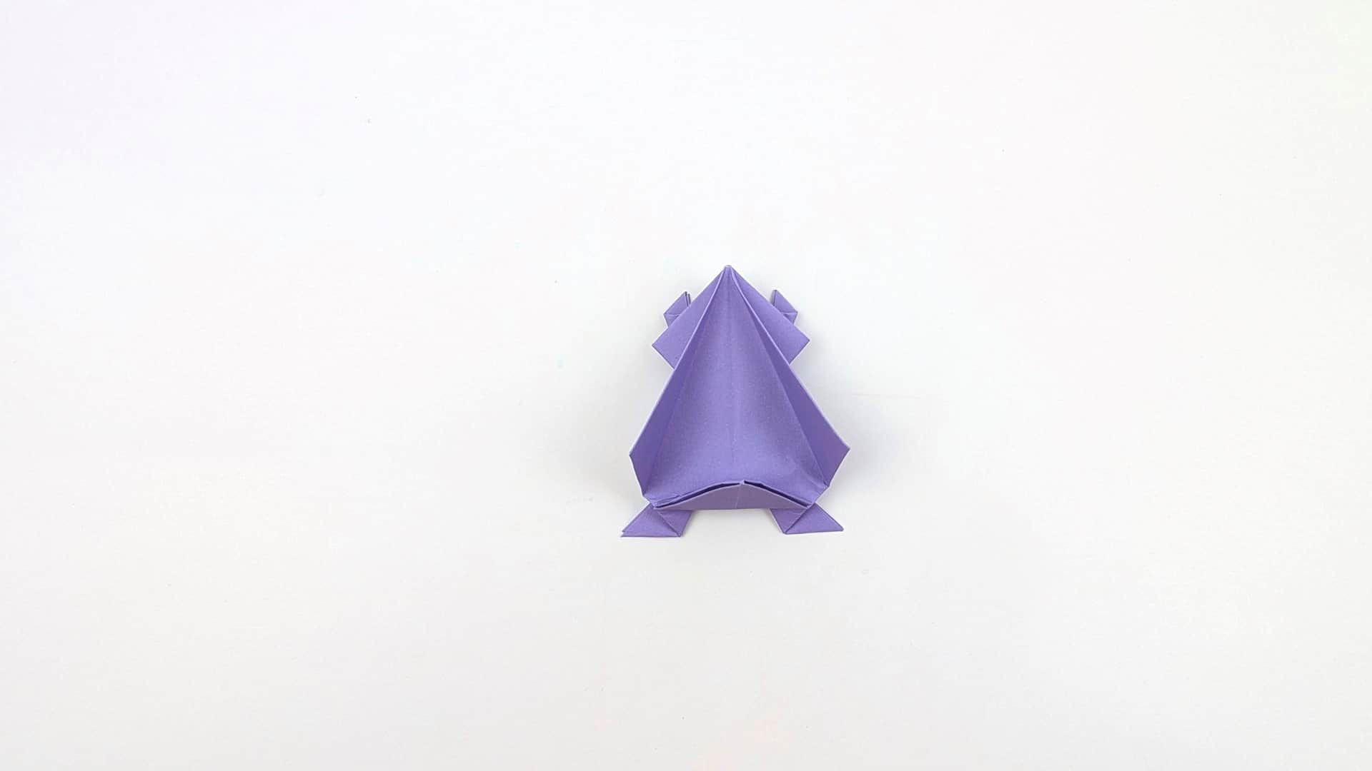Press the front of the body inward to round out the frog's belly. The head peak is smooth and the spring fold at the base is taking shape.