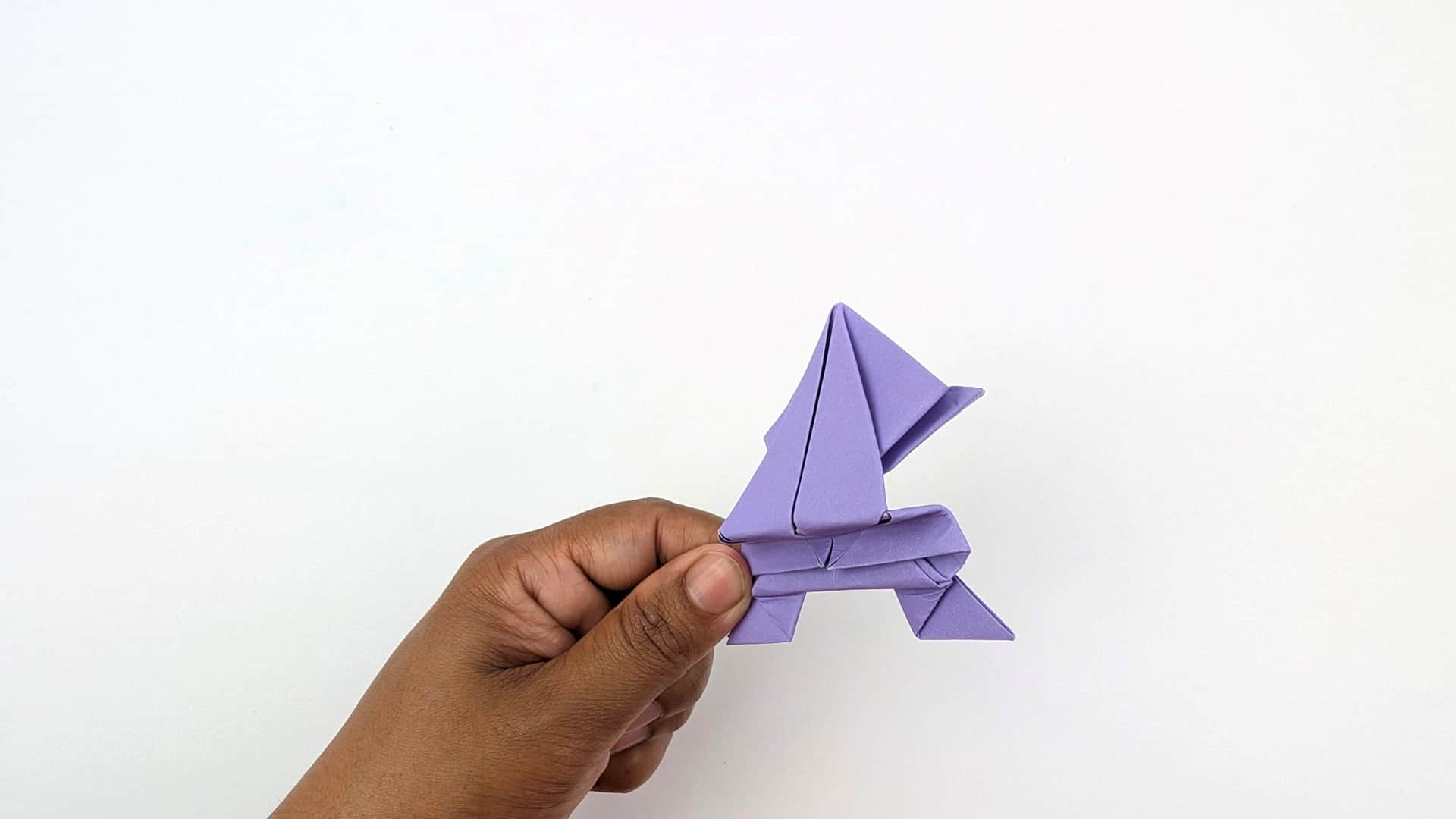 Side profile held in hand — the full frog silhouette is visible: head, rounded body arch, and all four legs.