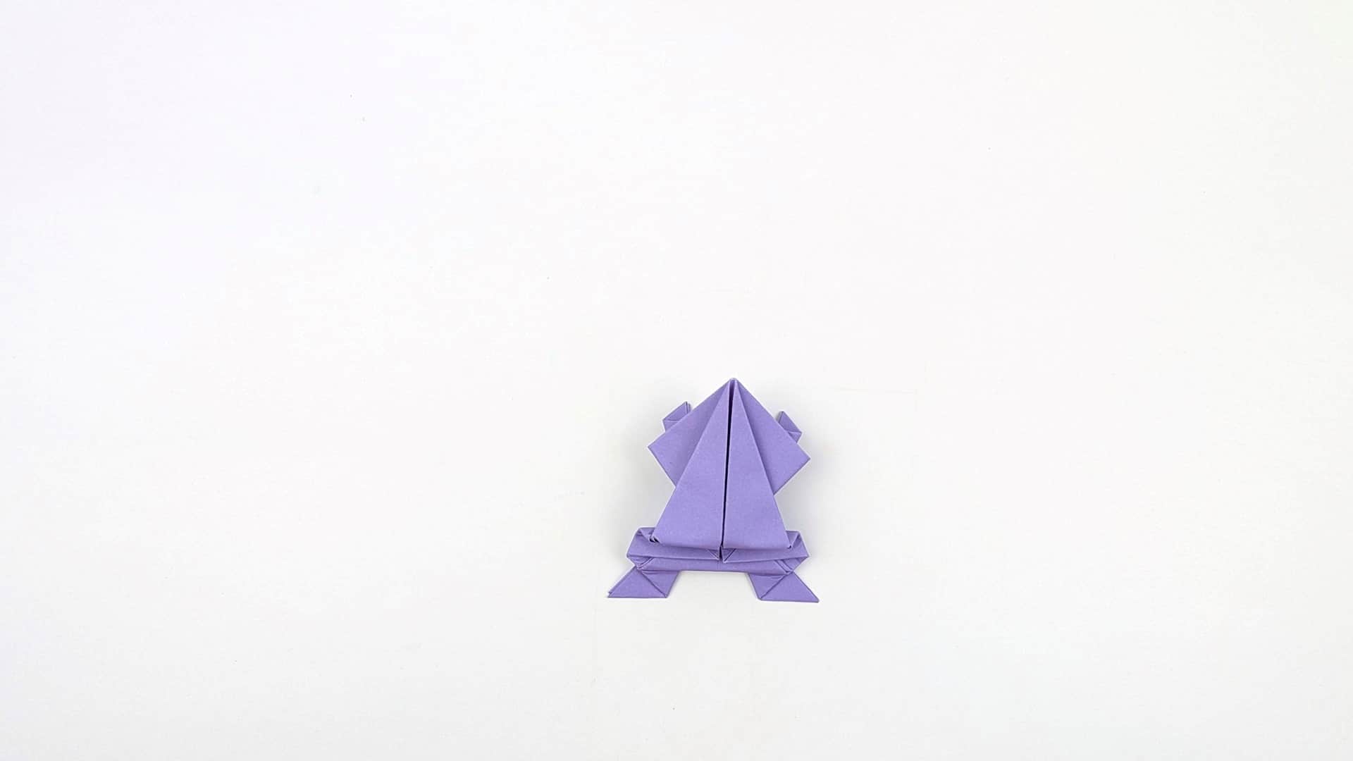 Place the frog flat on the surface, face forward. Front arms spread wide, back feet flat — it is ready to jump.