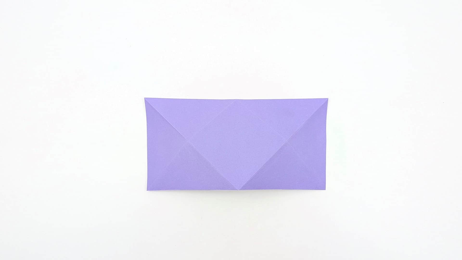 Fold both short ends inward so their corners meet at the center, forming an envelope shape with pointed triangular flaps.